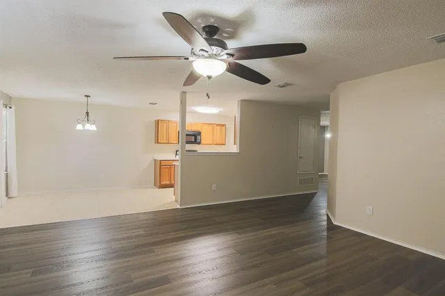 an empty room with wooden floor ceiling fan and windows