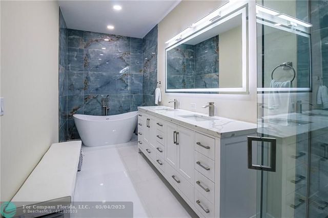 a bathroom with a double vanity sink mirror and bathtub
