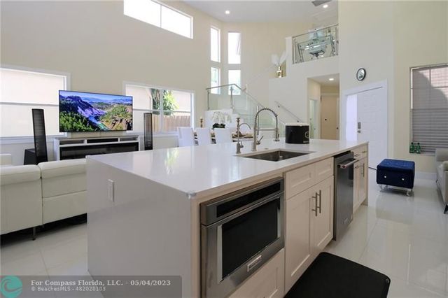 a spacious kitchen with stainless steel appliances a stove a sink and a microwave