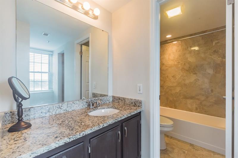 199 14th Street Northeast, Unit 705 Atlanta, GA 30309 - Photo 17 of 20 a bathroom with a granite countertop sink and a mirror