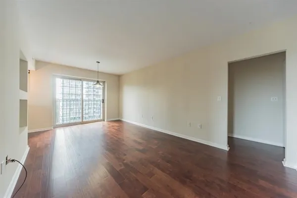 a view of an empty room with wooden floor and window