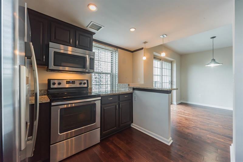 199 14th Street Northeast, Unit 705 Atlanta, GA 30309 - Photo 8 of 20 a kitchen with granite countertop wooden floors and stainless steel appliances