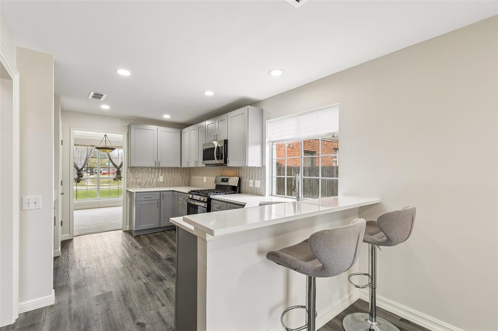 133 Hanover Street Grand Prairie, TX 75052 - Photo 9 of 31 a kitchen with stainless steel appliances kitchen island granite countertop a stove a sink and a refrigerator with wooden floor