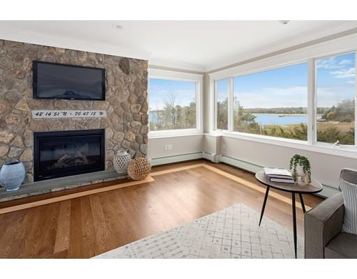 62 White Head Road Cohasset, MA 02025 - Photo 8 of 30 a living room with a fireplace a flat screen tv and a floor to ceiling window