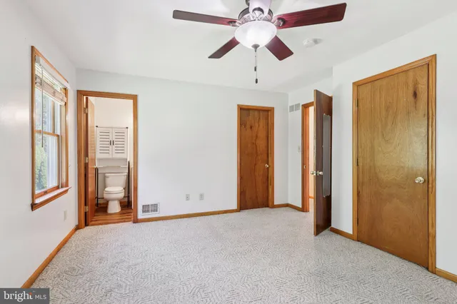 an empty room with chandelier fan and windows