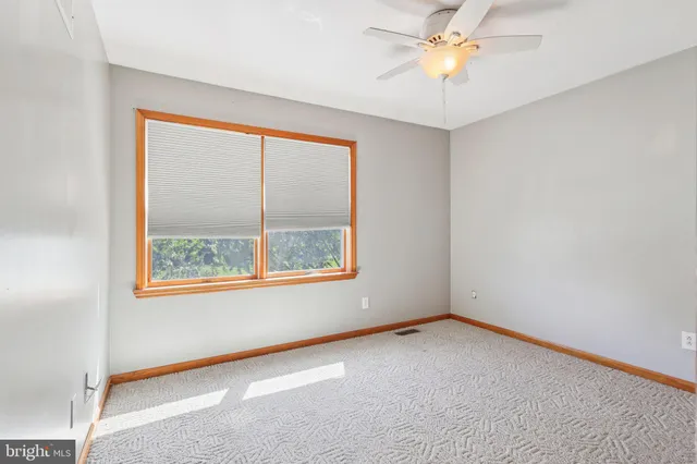 an empty room with a window and a fan