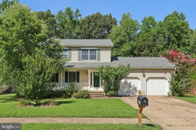 a front view of a house with a garden and trees
