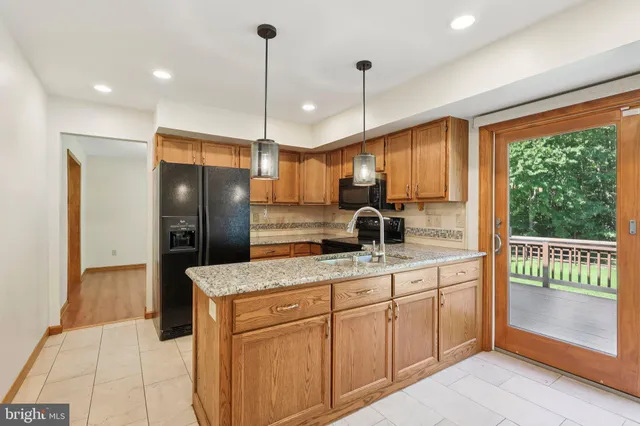 a kitchen with kitchen island granite countertop a refrigerator a sink and wooden cabinets