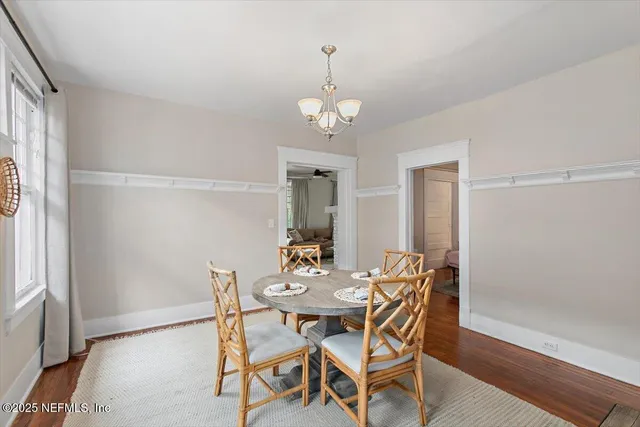 a dining room with wooden floor a chandelier a wooden table and chairs