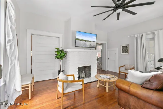 a living room with furniture a fireplace and a ceiling fan