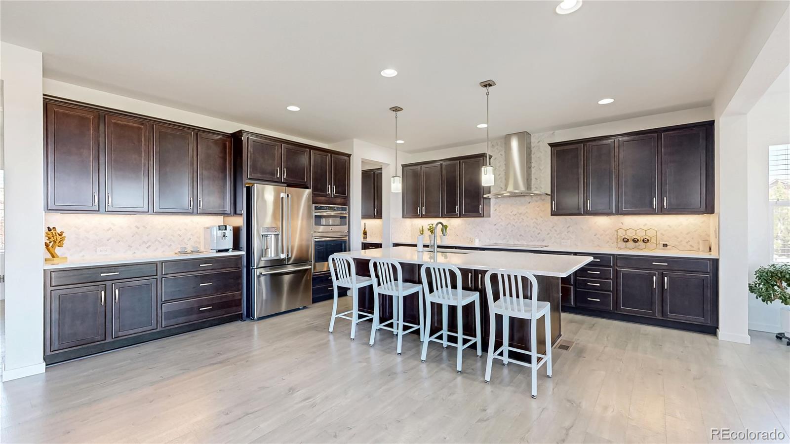 13950 Box Turtle Loop Parker, CO 80134 - Photo 10 of 48 a kitchen with stainless steel appliances granite countertop a refrigerator a oven a sink a dining table and chairs with wooden floor