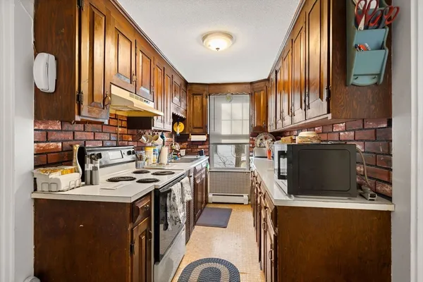 a kitchen with stainless steel appliances granite countertop a stove a sink dishwasher and a microwave oven with large trees