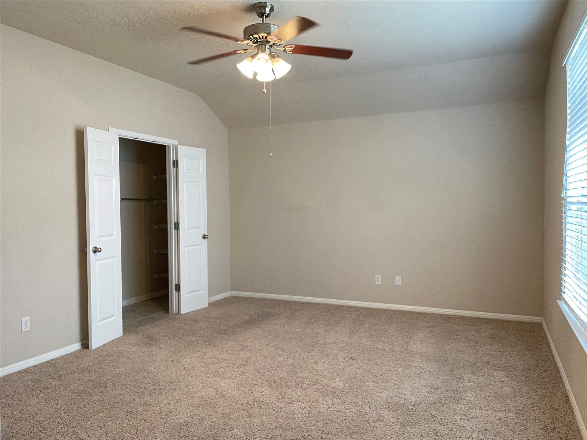 11713 Dunblane Way Austin, TX 78754 - Photo 12 of 22 Spacious room featuring neutral carpet flooring, a vaulted ceiling, and a ceiling fan with integrated lighting