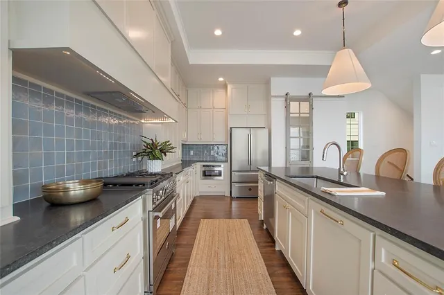 a kitchen with stainless steel appliances granite countertop a sink a stove and a wooden floors