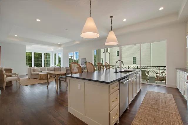 a kitchen with granite countertop a stove a sink a dining table and chairs with wooden floor