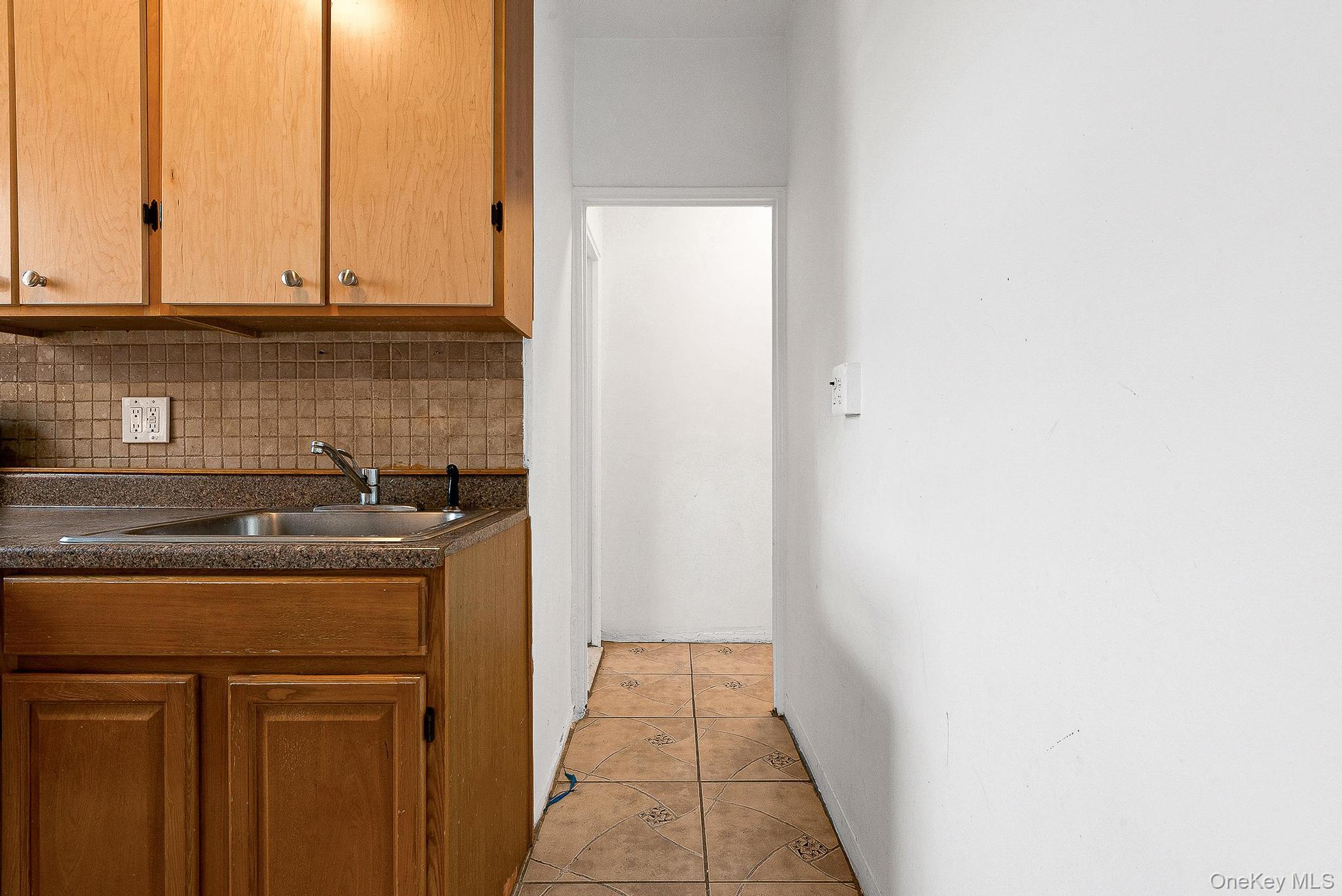 99-32 66th Road, Unit 5B Queens, NY 11374 - Photo 10 of 27 Kitchen featuring dark countertops, light tile patterned flooring, and backsplash