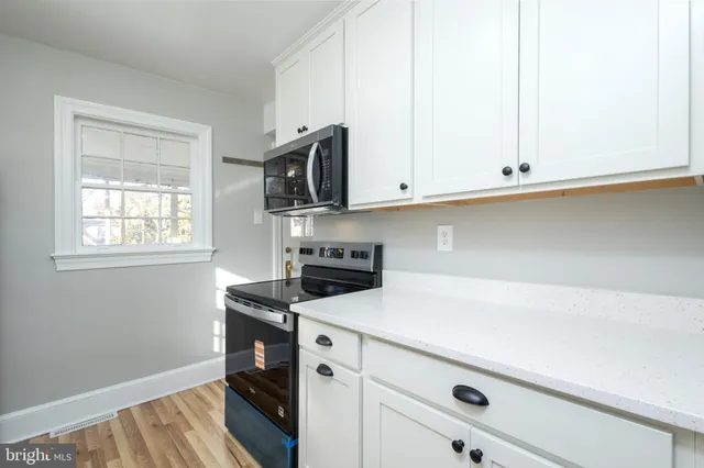 a kitchen with white cabinets and a wooden floor
