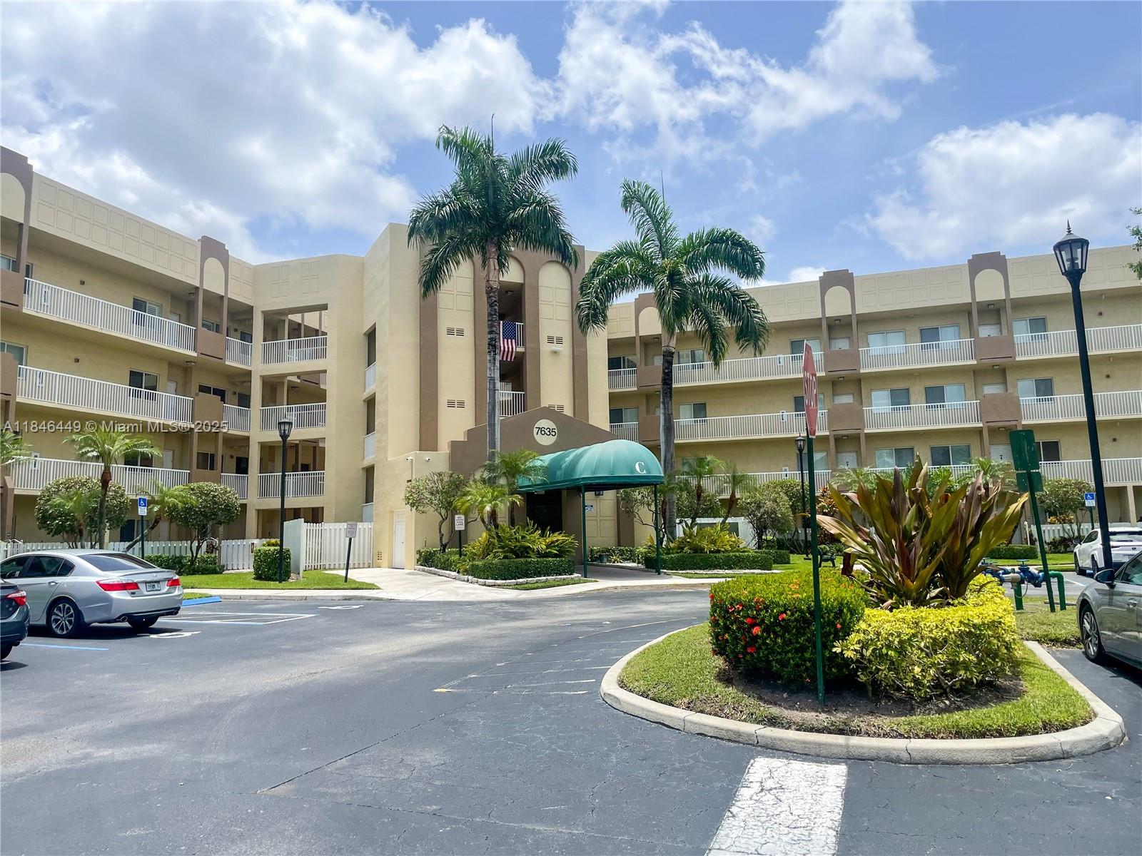 a front view of a building with garden and parking