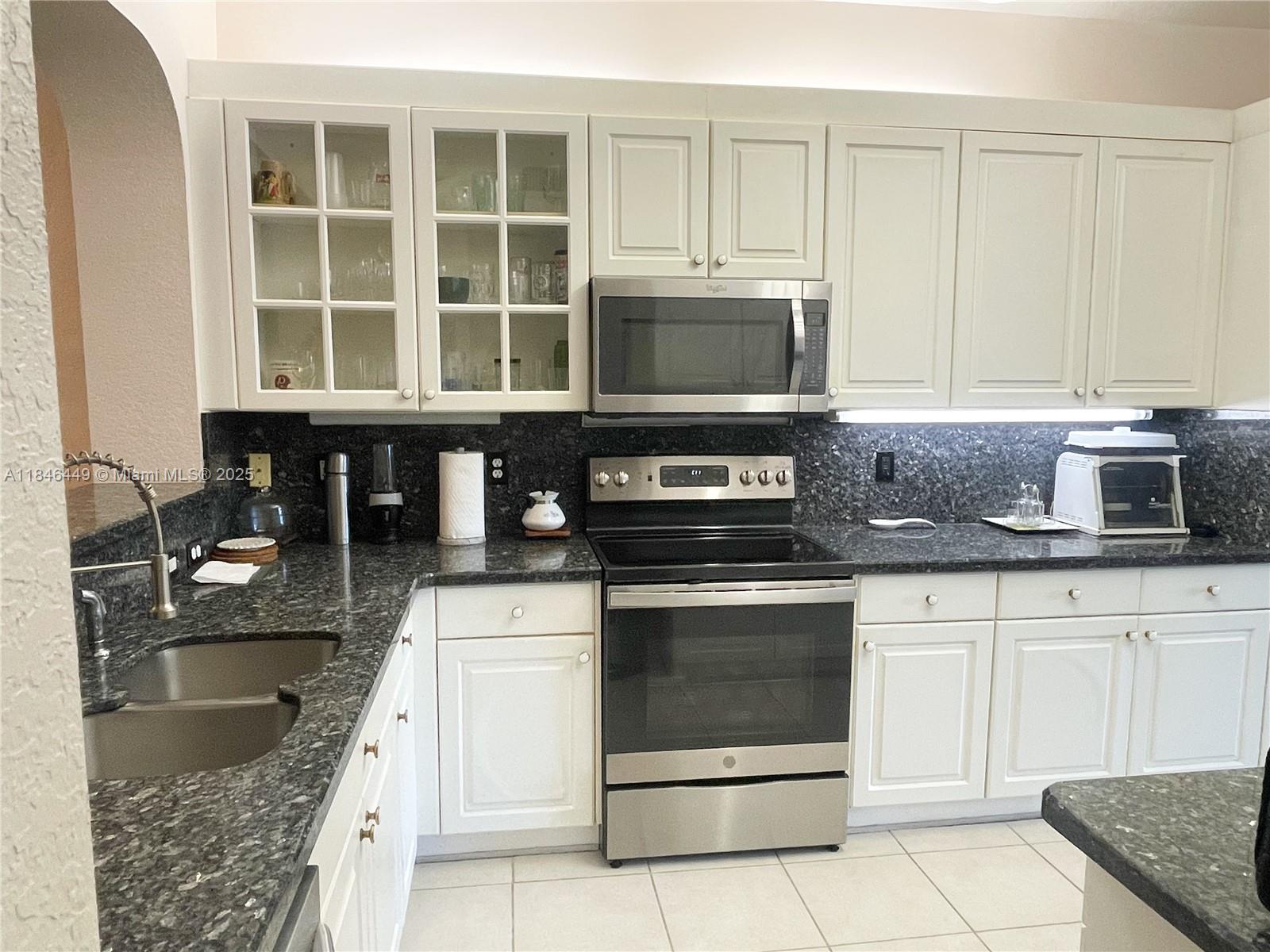 7635 Southampton Terrace, Unit 201 Tamarac, FL 33321 - Photo 2 of 23 a kitchen with granite countertop a stove sink and cabinets