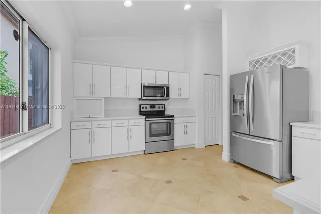 a kitchen with a refrigerator stainless steel appliances wooden floor and a window