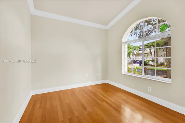 a view of empty room with window and wooden floor