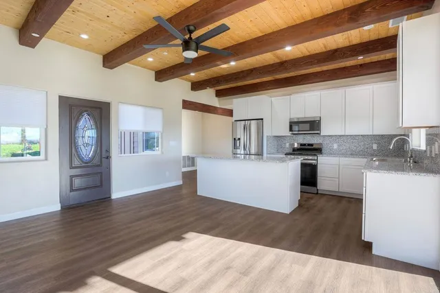 a kitchen with granite countertop a refrigerator cabinets and wooden floor