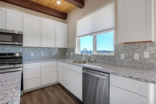 a kitchen with stainless steel appliances granite countertop a sink a stove and cabinets