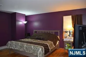 a bedroom with a bed and a flat tv screen on dresser