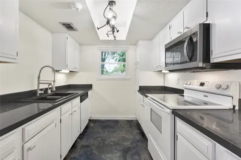 a kitchen with granite countertop a sink stainless steel appliances and cabinets