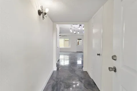a view of an empty room with chandelier fan and windows