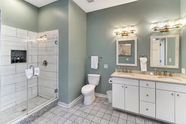 a bathroom with a double vanity sink a toilet and shower