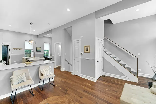 a large white kitchen with wooden floor and furniture
