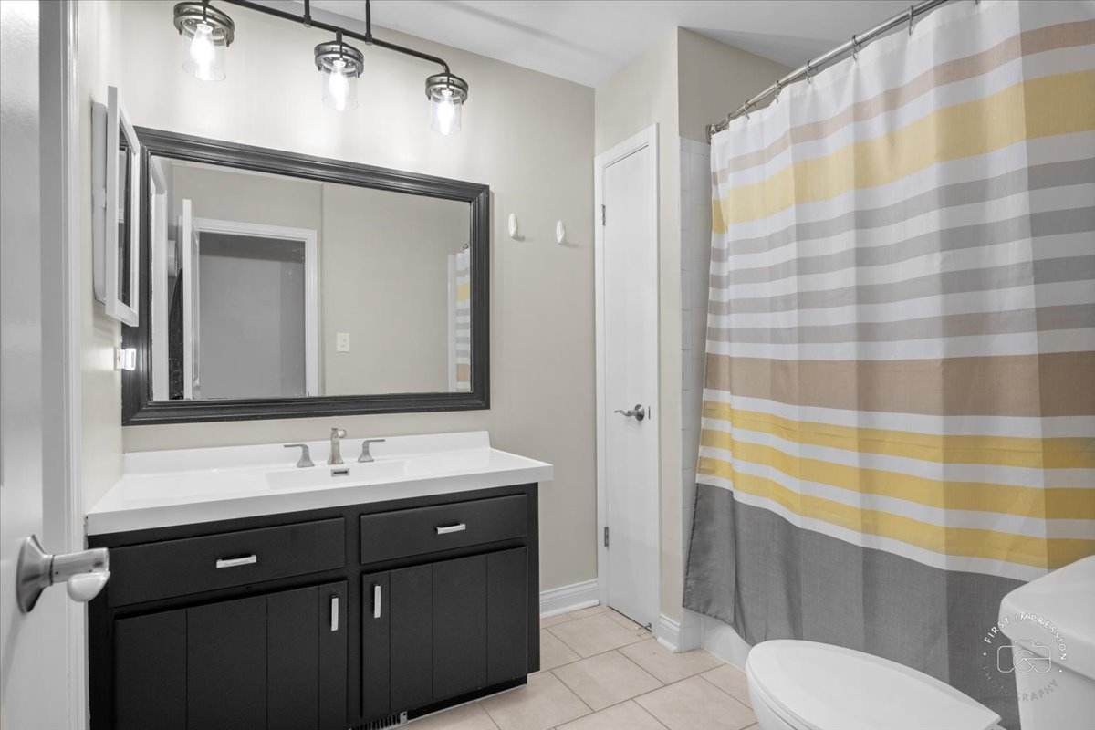 1015 Heathrow Court Wheaton, IL 60189 - Photo 12 of 18 a bathroom with a sink a toilet a mirror and shower curtain