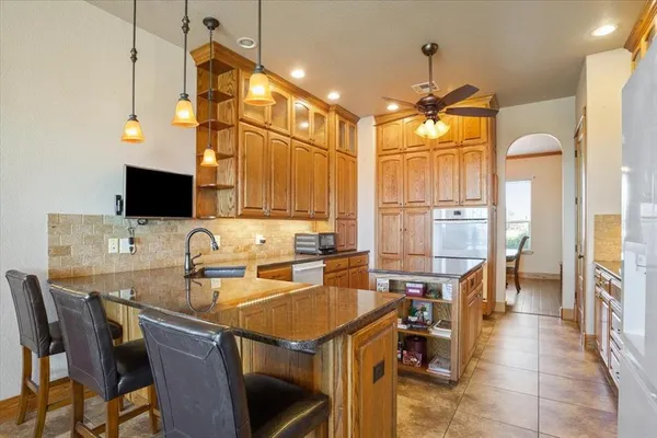 a kitchen with granite countertop a sink a counter top space appliances and cabinets