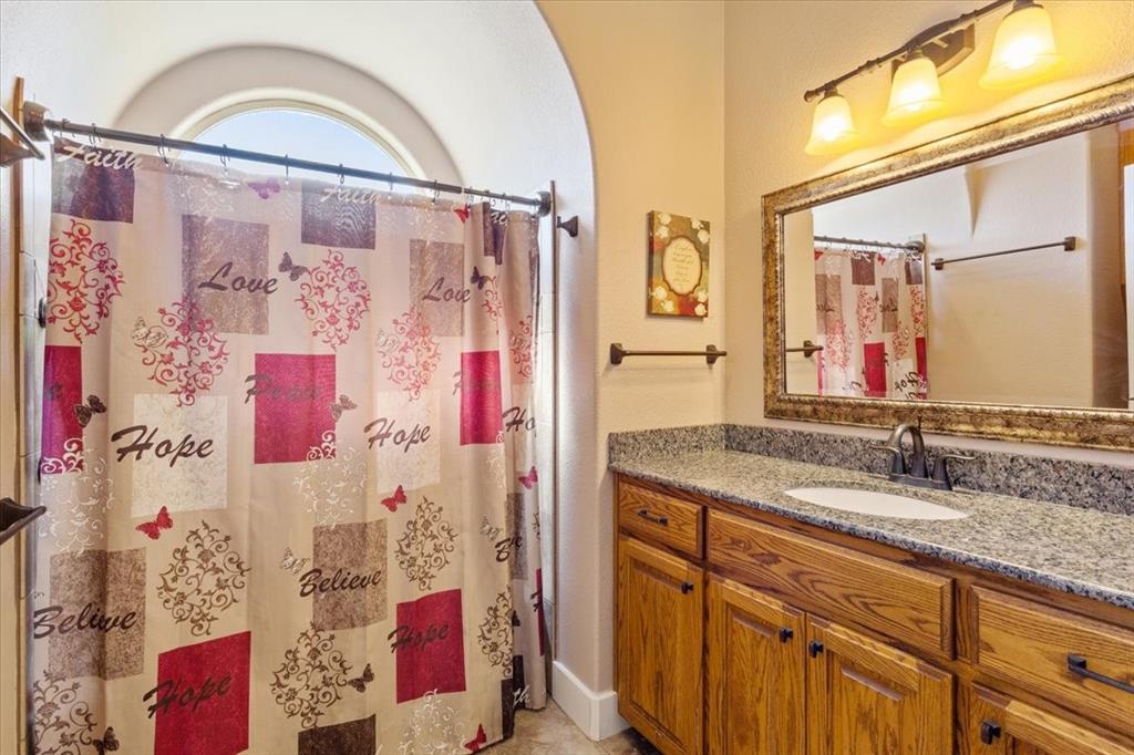 10479 Hartrick Bluff Road Little River-Academy, TX 76554 - Photo 29 of 40 a bathroom with a granite countertop sink a mirror a shower and vanity