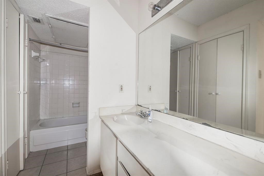 7900 North Stadium Drive, Unit 22 Houston, TX 77030 - Photo 3 of 12 This bathroom features a simple design with a large mirror, single-sink vanity, and a bathtub with a tiled shower area. It includes ample cabinet storage and has a neutral color scheme.