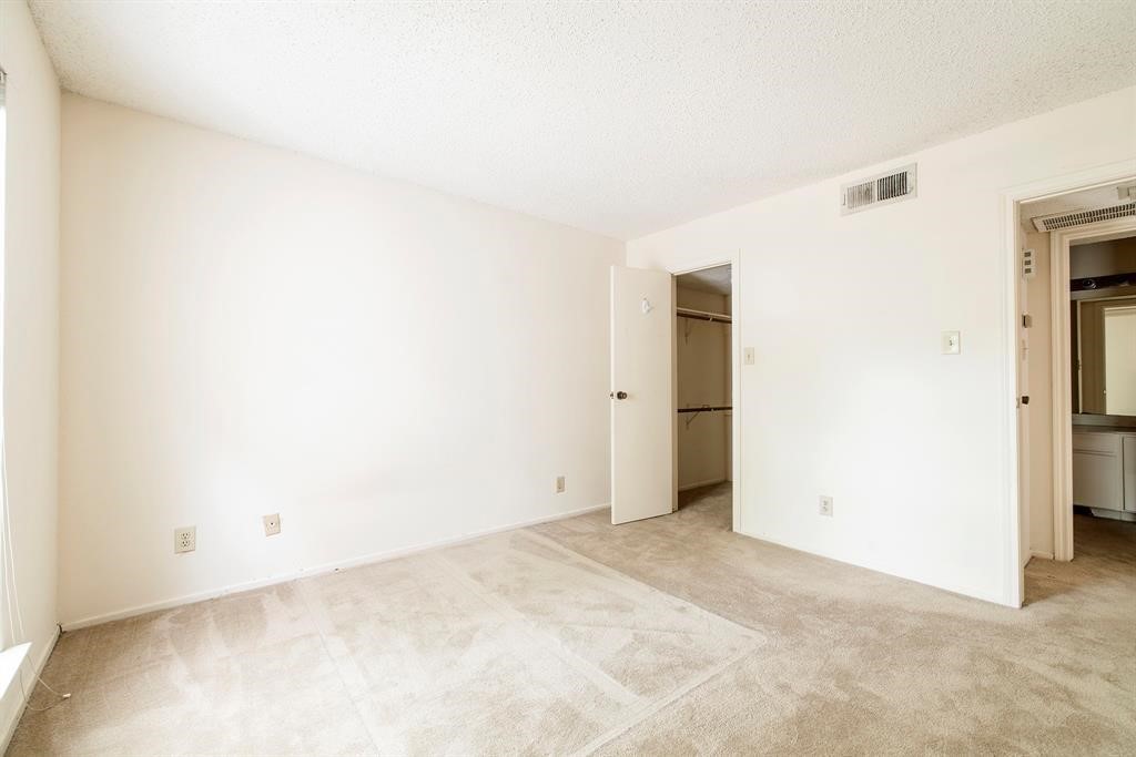 7900 North Stadium Drive, Unit 22 Houston, TX 77030 - Photo 4 of 12 This photo shows a bright, empty room with neutral walls and carpet. It features a small closet and visible air vent, with a doorway leading to another area, possibly a bathroom. Ideal for customization.
