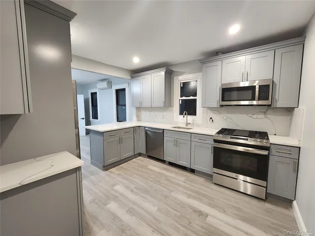 a kitchen with stainless steel appliances kitchen island granite countertop a sink a stove top oven and wooden floors