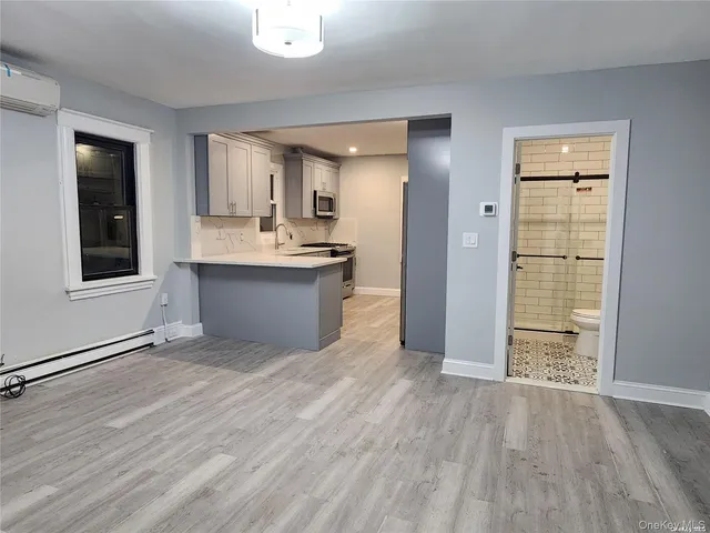 an empty room with wooden floor and a kitchen