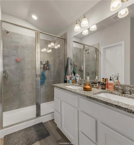 a bathroom with double vanity and a mirror