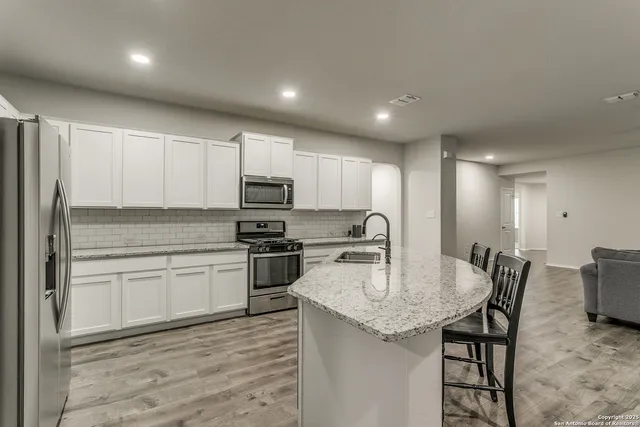 a kitchen with stainless steel appliances granite countertop a kitchen island hardwood floor sink and stove