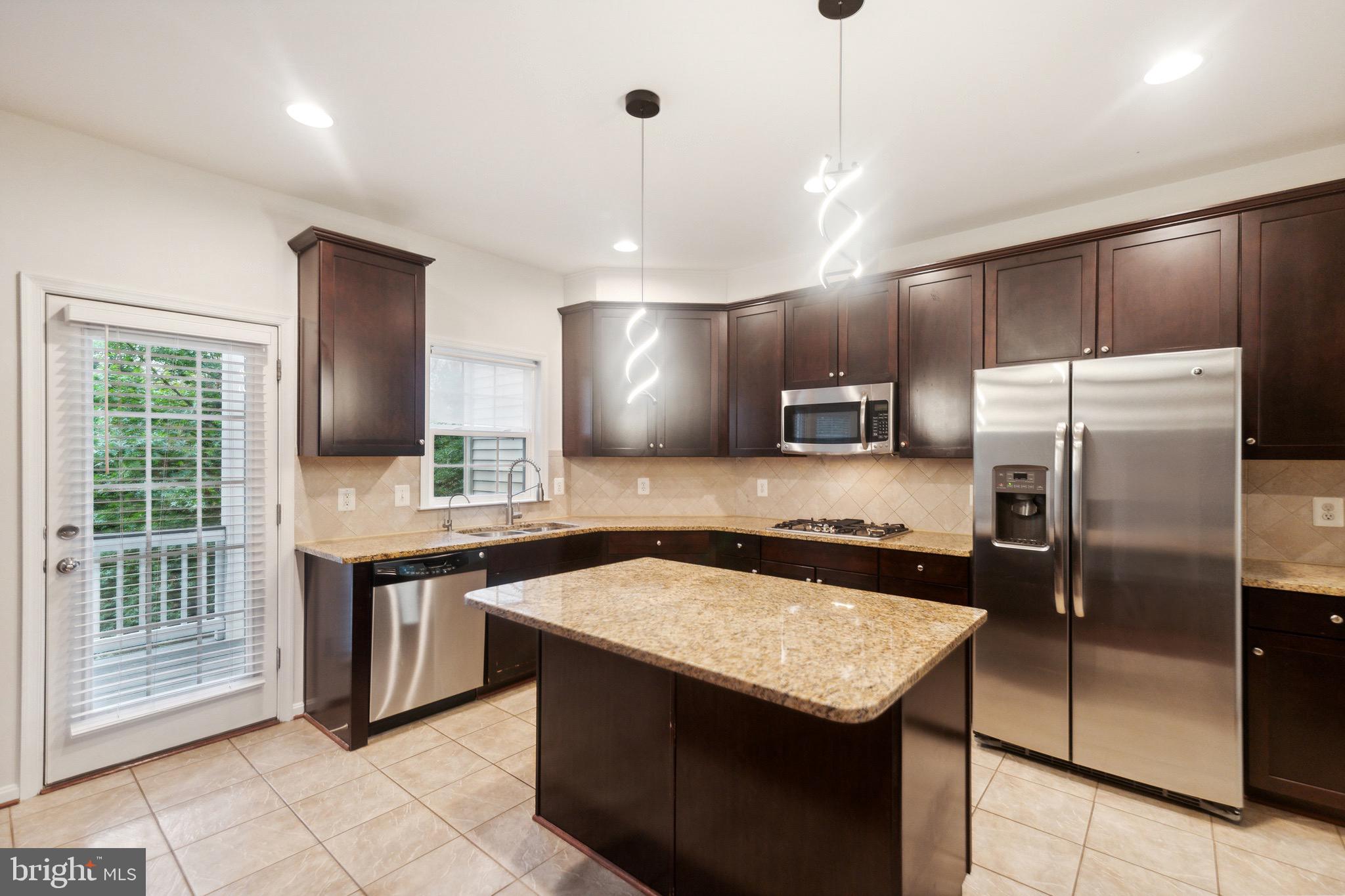 42385 Trellis Square Brambleton, VA 20148 - Photo 11 of 28 a kitchen with stainless steel appliances granite countertop a sink a stove a refrigerator and island