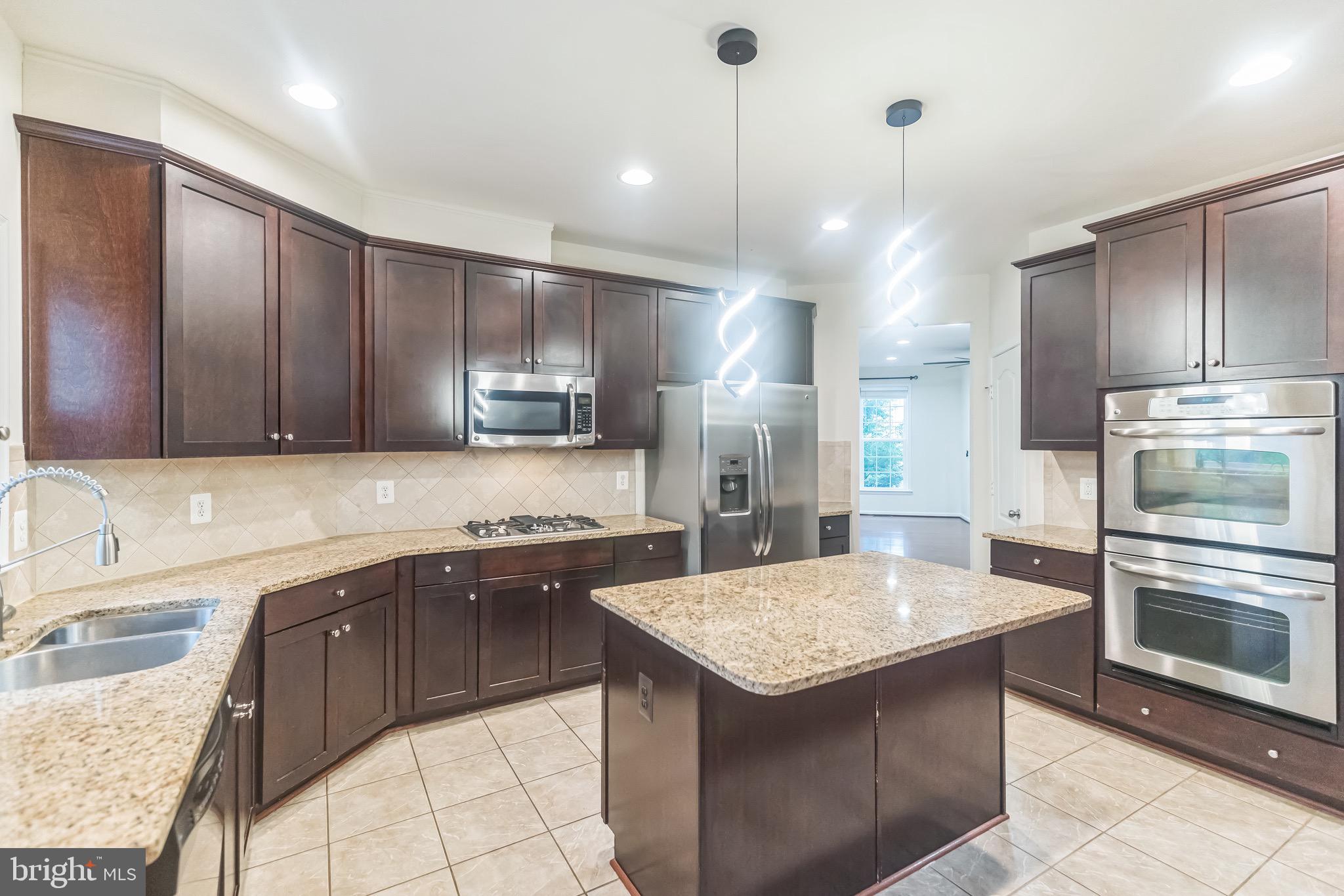 42385 Trellis Square Brambleton, VA 20148 - Photo 12 of 28 a kitchen with stainless steel appliances granite countertop a sink stove and refrigerator