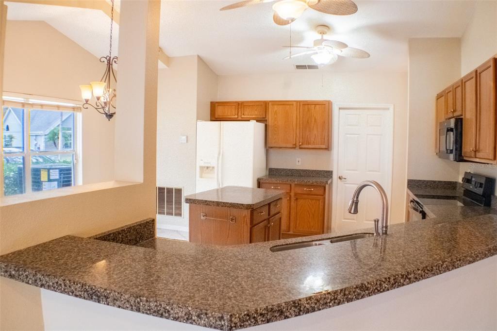 601 Shady Point Way Deland, FL 32724 - Photo 15 of 33 a kitchen with kitchen island granite countertop a sink a counter top space cabinets and stainless steel appliances