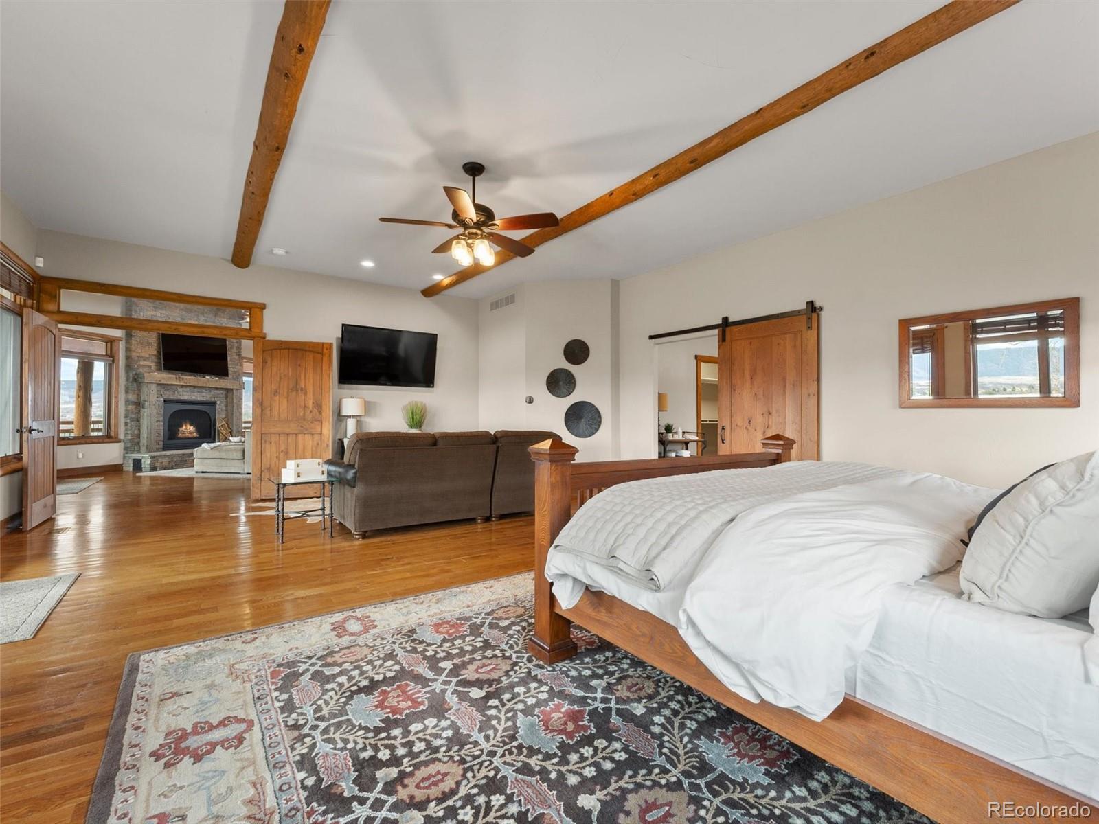 934 South Perry Park Road Sedalia, CO 80135 - Photo 24 of 48 a spacious bedroom with a large bed a flat tv screen and a rug