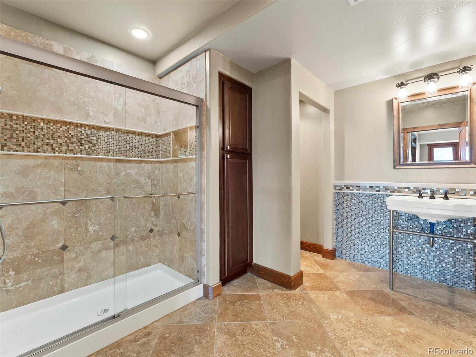 934 South Perry Park Road Sedalia, CO 80135 - Photo 40 of 48 a bathroom with a granite countertop sink mirror and shower
