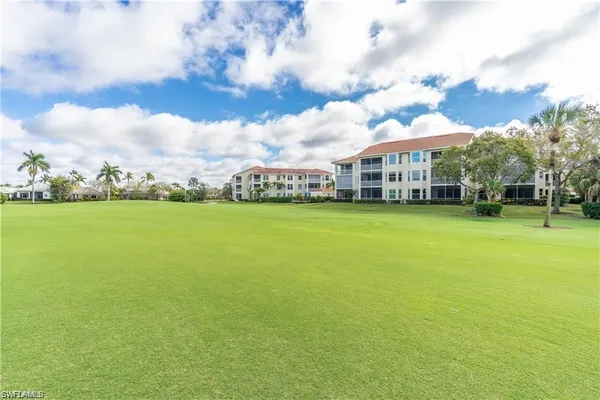 a view of a building with a big yard and large trees