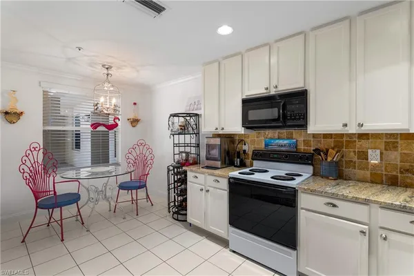 a kitchen with stainless steel appliances a stove a sink dishwasher a microwave oven with white cabinets and wooden floor