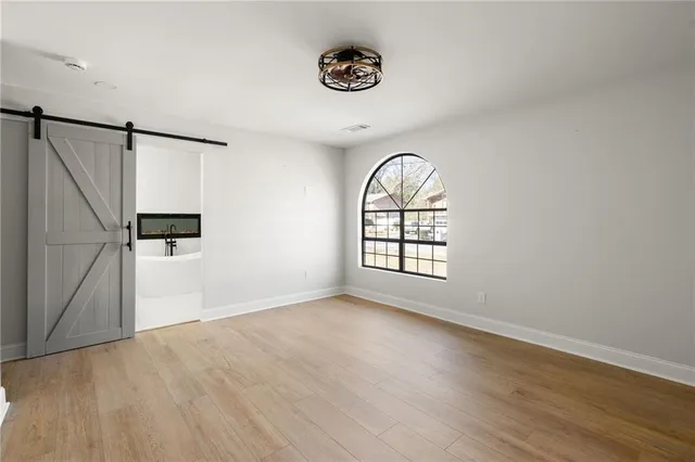 an empty room with wooden floor cabinet and windows