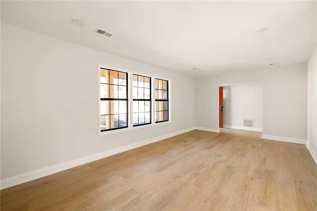 an empty room with wooden floor and windows